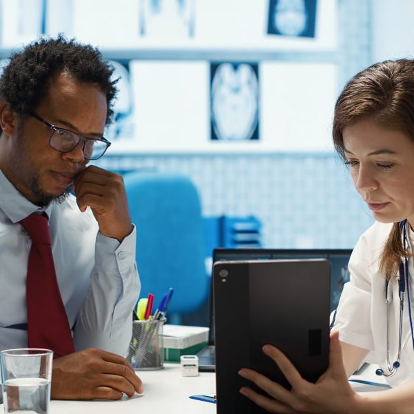 General practitioner presenting the test findings via scan interpretation on tablet, discussing about the diagnostic and possible treatment. Medical expert provides advice to patient. Camera A.